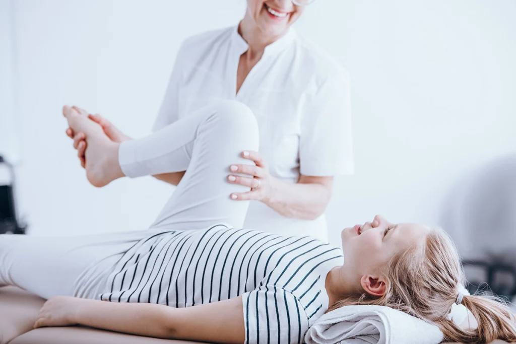 A physical therapist working with a child on a treatment table