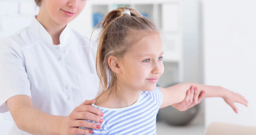 A physical therapist guiding a young girl through an exercise